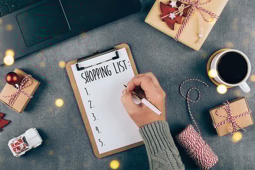 Christmas online shopping flat lay. Women writing shopping list on table. Laptop, present box, cup of coffee, Christmas holiday decoration photo
