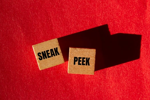Sneak peek message written on wooden cubes with red background. Conceptual sneak peek symbol. Copy space. photo