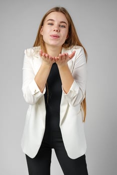 Young Woman Blowing Kiss While Wearing a White Blazer and Black Top photo
