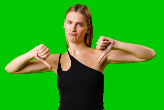 Young Woman Expressing Disapproval With a Thumbs Down Gesture Against a Green Background photo