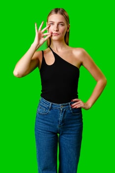 Young Woman Gesturing Silence With Finger on Lips Against Green Screen Background photo
