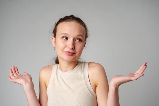 Young Clueless Woman Standing With Outstretched Arms on gray background photo