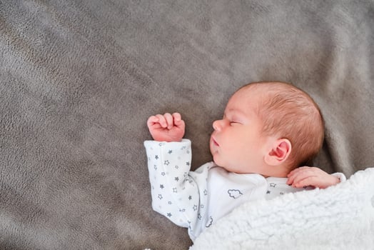 Baby newborn sleeping covered on gray woolen blanket photo