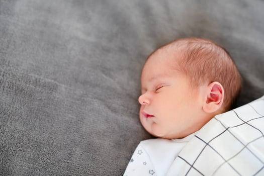 Smiling baby girl lying on a bed sleeping on gray sheets photo