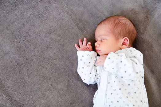 Peaceful baby lying on a bed while sleeping in a bright room. photo