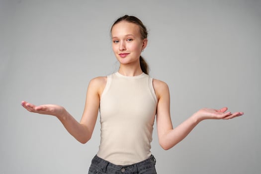 Young Clueless Woman Standing With Outstretched Arms on gray background photo