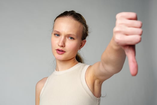 Young Woman Giving Thumbs Down Gesture Against a Neutral Background. photo