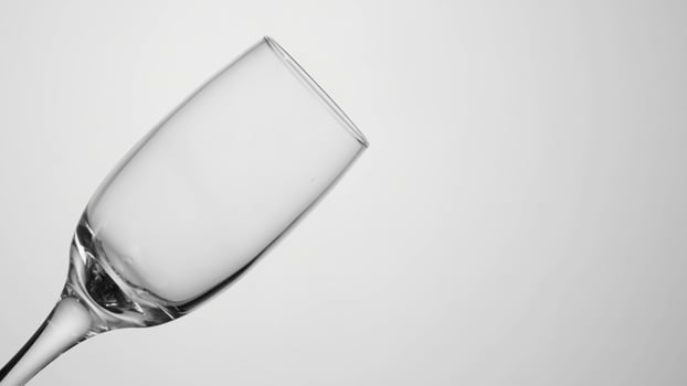Transparent glass cup on isolated background. Action. Empty transparent glass stands on light isolated background. Empty glass without liquid photo