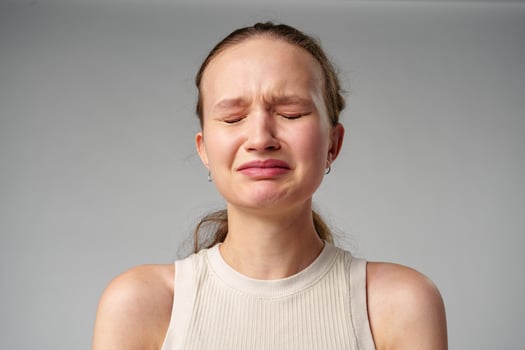 Young Woman Grimacing in Displeasure Against a Neutral Background photo