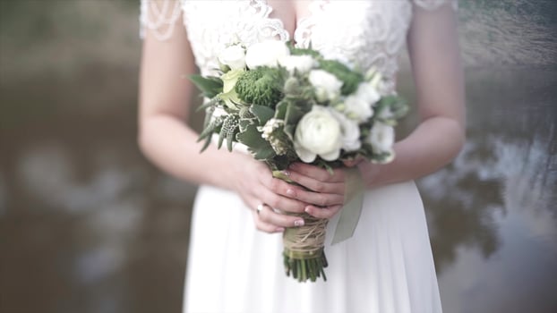 Beautiful bouquet of different colors in the hands of the bride in a white dress. Bride in white dress with bouquet. Woman holds wedding bouquet. Wedding photo