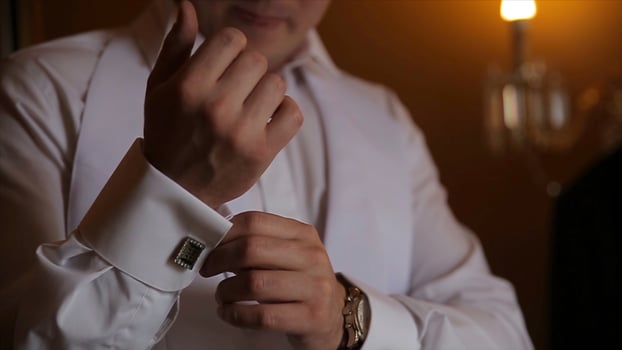 Groom is holding hands on the tie, wedding suit. close up of a hand man how wears white shirt and cufflink. Business man fixing black tie on white shirt. Groom on wedding day fixing tie, vintage photo