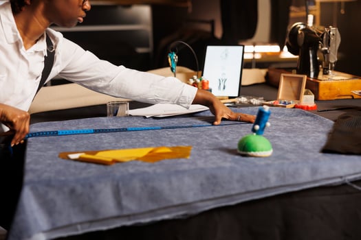 Skilled tailor doing fabric measurements in professional atelier shop workspace. Professional experienced seamstress manufacturing bespoken elegant stylish sartorial upcoming collection photo