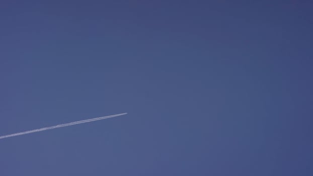 Large passenger supersonic plane flying high in clear blue sky, leaving long white trail. Airplane flying in white clouds in a blue sky. Airplane flying blue sky photo