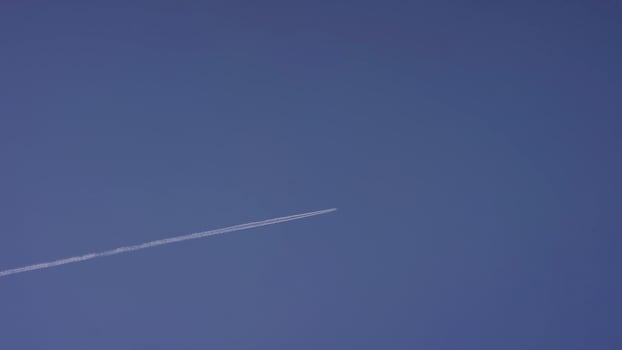 Large passenger supersonic plane flying high in clear blue sky, leaving long white trail. Airplane flying in white clouds in a blue sky. Airplane flying blue sky photo