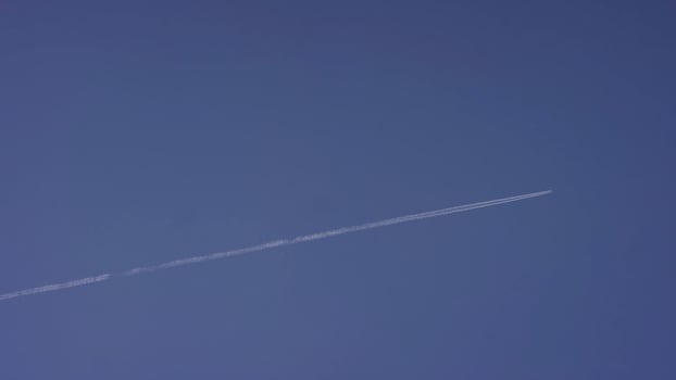Large passenger supersonic plane flying high in clear blue sky, leaving long white trail. Airplane flying in white clouds in a blue sky. Airplane flying blue sky photo