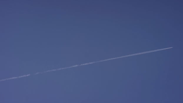 Large passenger supersonic plane flying high in clear blue sky, leaving long white trail. Airplane flying in white clouds in a blue sky. Airplane flying blue sky photo