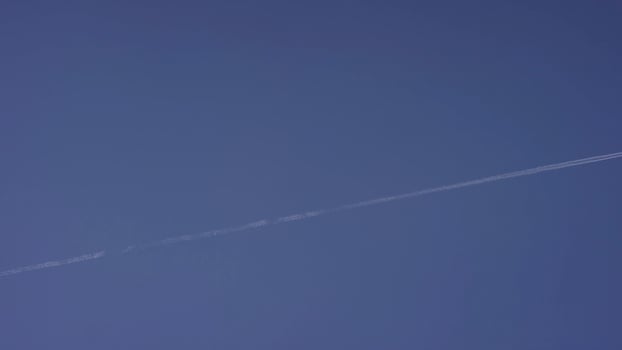 Large passenger supersonic plane flying high in clear blue sky, leaving long white trail. Airplane flying in white clouds in a blue sky. Airplane flying blue sky photo