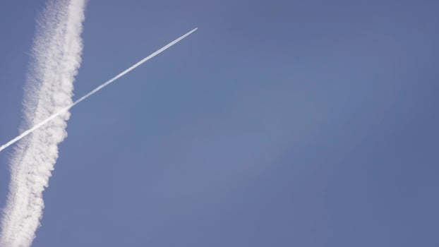 Large passenger supersonic plane flying high in clear blue sky, leaving long white trail. Airplane flying in white clouds in a blue sky. Airplane flying blue sky photo