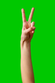 Hand Making Peace Sign Gesture Against Vibrant Green Background photo