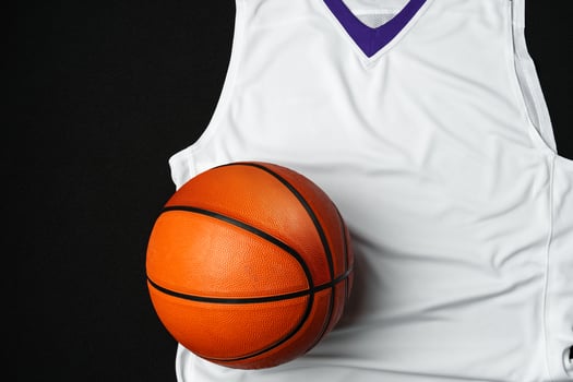 Close-Up of Basketball and White and Purple Jersey on a Black Background photo