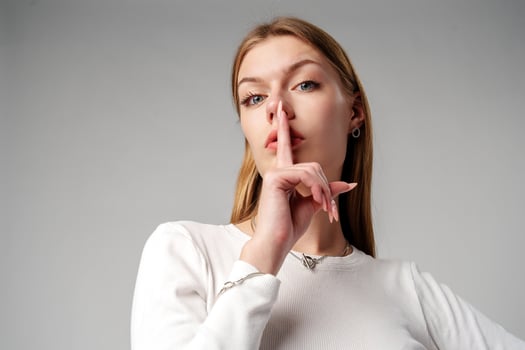Woman Posing With Finger on Lips Hush Sign in Studio photo