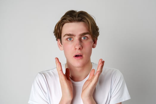 Young Man With Surprised Expression and Hands Raised in Studio Setting photo