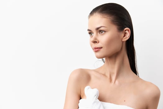 A graceful portrait featuring a young woman with glowing skin and straight wet hair, set against a photo