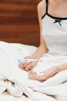 Ill woman sitting in bed with thermometer and glass of water. photo