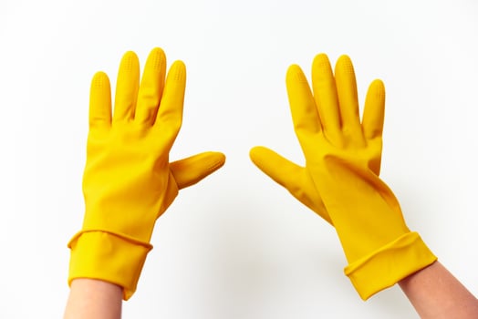 Rubber yellow gloves held up by a hand on a white surface. photo