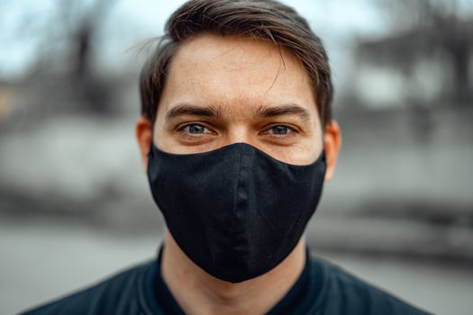 Portrait man in medical mask. Young man stands on light background and looking at camera. COVID-19 Pandemic Coronavirus. photo