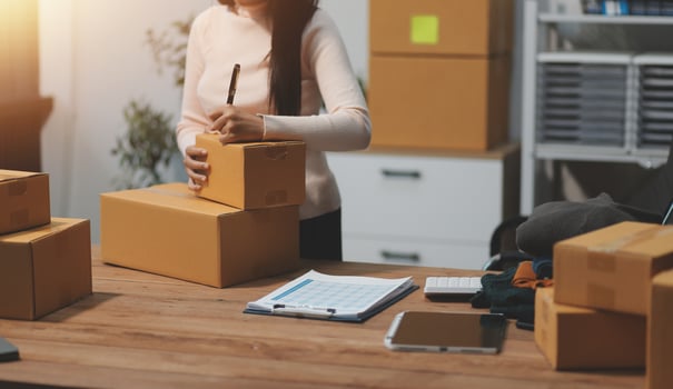 Startup SME small business entrepreneur of freelance Asian woman wearing apron using laptop and box to receive and review orders online to prepare to pack sell to customers, online sme business ideas. photo