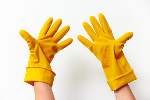 Pair of yellow rubber gloves held by two people against a white background. photo