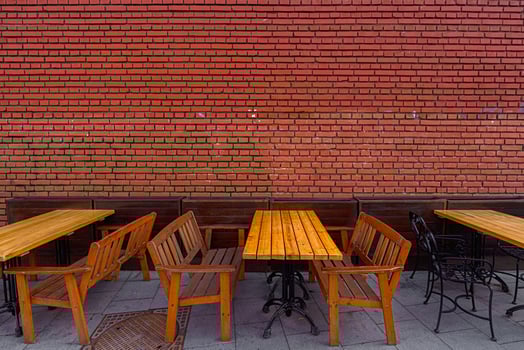 Wooden tables and chairs against a background of a red brick wall. photo