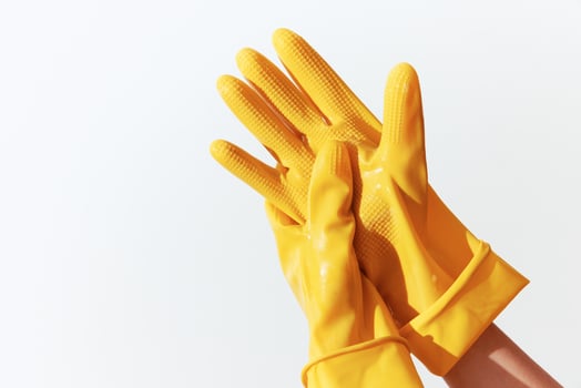 Pair of yellow rubber gloves held by a woman's hands on a white background with space for text photo