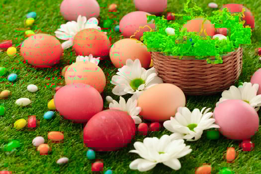Close up photo of colored Easter eggs and candies on grass