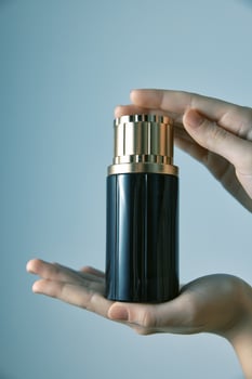 Black and gold perfume bottle held by person on blue background. a stylish and elegant image perfect photo