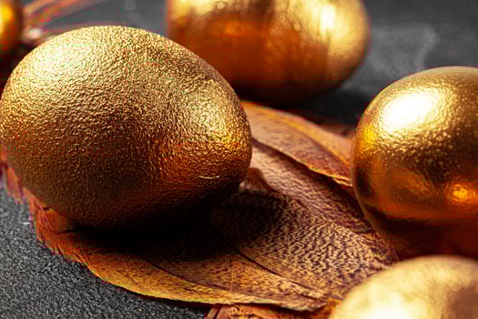 Golden Easter eggs on red bird feathers close up photo