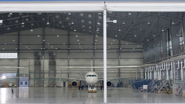 Roller shutter door and concrete floor of airport hangar and airplane background. Airport hangar from the outside with big tall doors. Front view. Aircraft Hangar photo