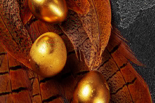 Golden Easter eggs on red bird feathers close up photo