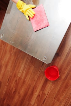 Woman cleaning glass table with mop and bucket of water on the floor. photo