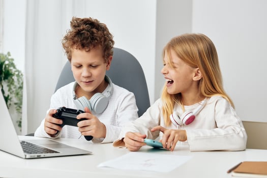 Happy Caucasian children, a boy and a girl, sitting at home in their living room, engrossed in photo