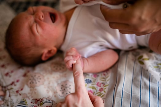 Newborn baby holding his mothers finger, selective focus photo