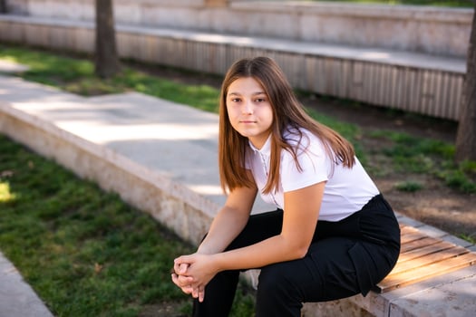 A 16-year-old girl in a school uniform sits on the steps of the street photo