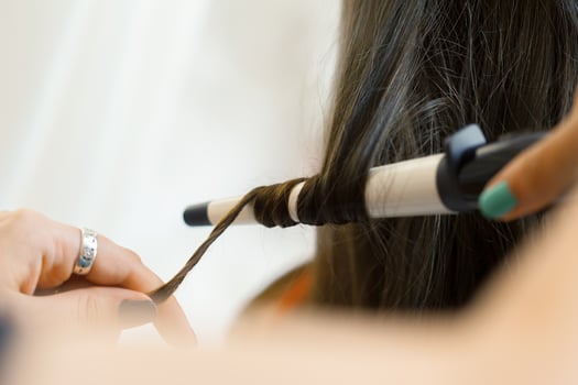 Hairstylist curling hair client in hairdressing salon photo
