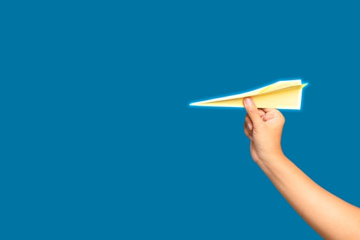 Business startup concept. Hand holding a yellow rocket paper on a blue background. photo