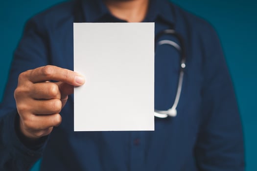 Doctor hand holding a blank white paper while standing on a blue background. photo
