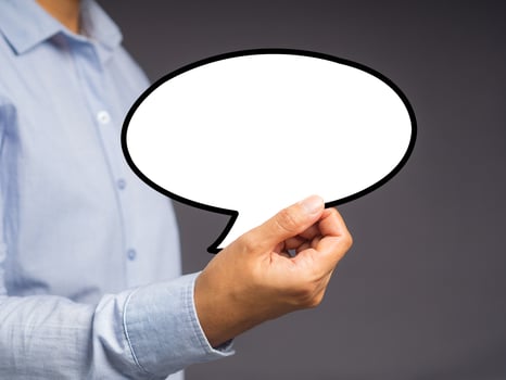 Hand holding of an empty white speech bubble against a gray background. photo