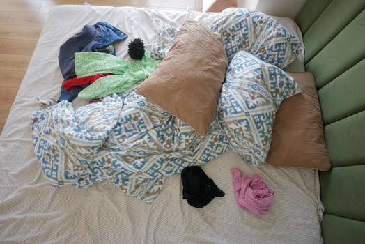 A Messy Bed with Various Colorful Clothes and Soft Pillows Is a Cozy and Casual Space photo