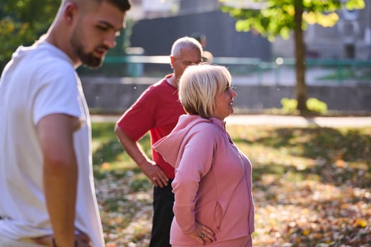 A group of seniors follows a trainer, engaging in outdoor exercises in the park, as they collectively strive to maintain vitality and well-being, embracing an active and health-conscious lifestyle in photo