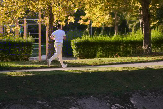 A handsome man maintains his healthy lifestyle as he runs along beautiful natural trails, embodying the essence of fitness, wellness, and vitality in the midst of scenic outdoor surroundings. photo